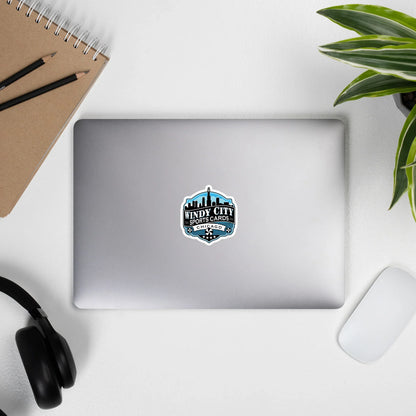 Windy City logo sticker, 3 by 3 inches, on a laptop beside headphones