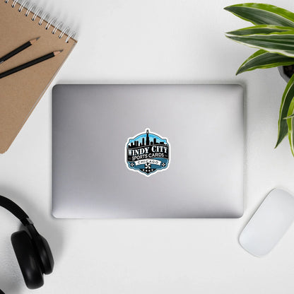 Windy City logo sticker, 4 by 4 inches, on a laptop beside headphones