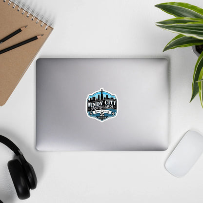 Windy City logo sticker, 5.5 by 5.5 inches, on a laptop beside headphones